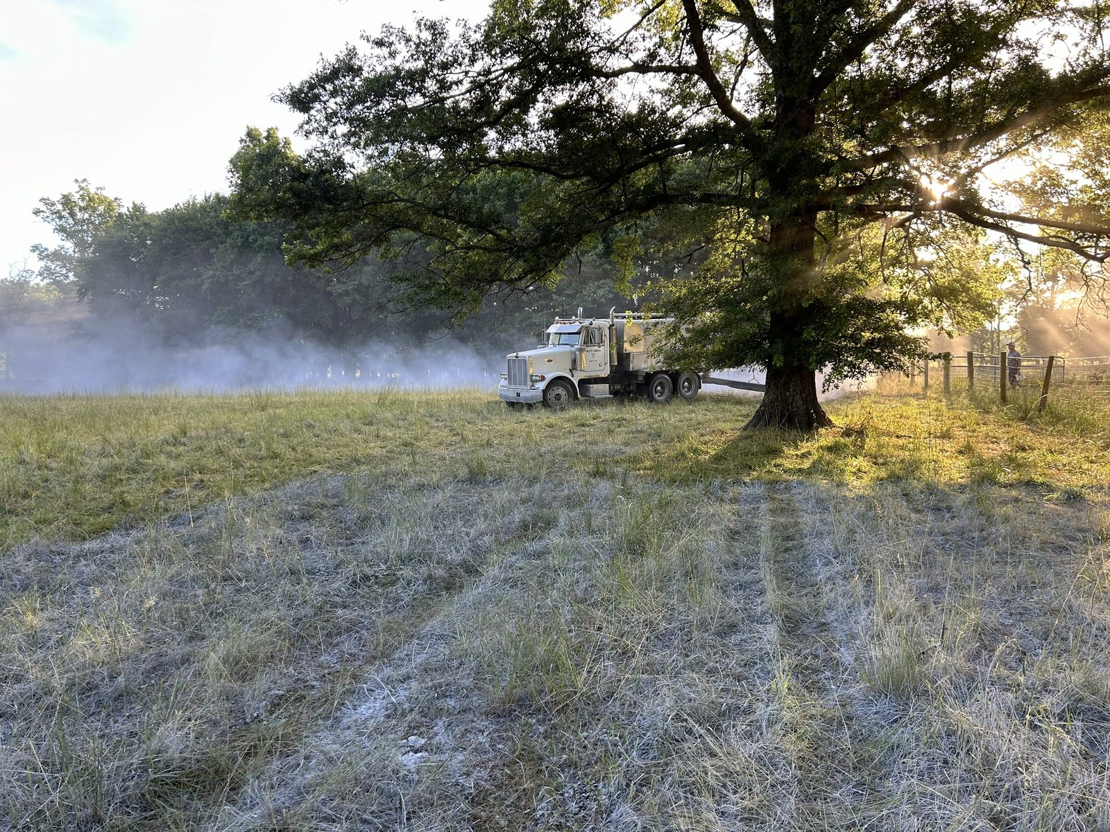 Lime application underway on a farm field in early morning haze